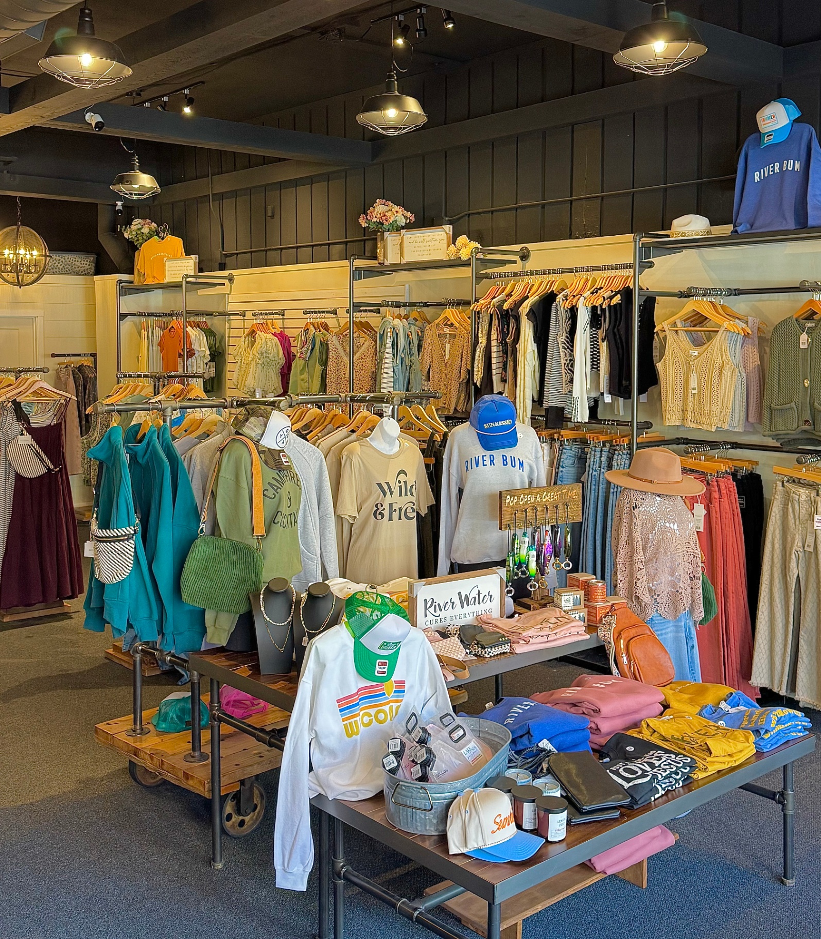 Inside The Custom Edit boutique with racks of apparel, graphic tees, hats, and gift displays under warm pendant lighting